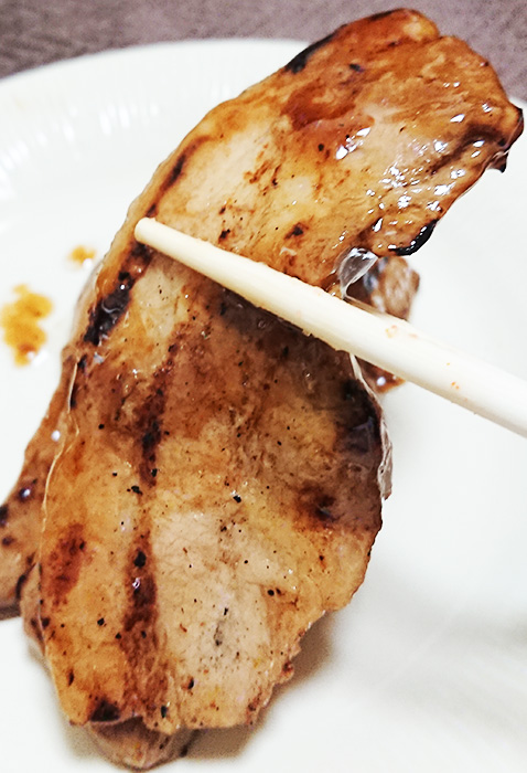 「豚バラの炭火焼」を箸でつまんだ写真